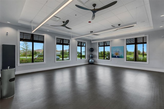 exercise room featuring a raised ceiling and ceiling fan