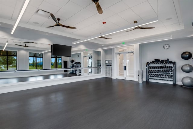 exercise area featuring a tray ceiling and ceiling fan