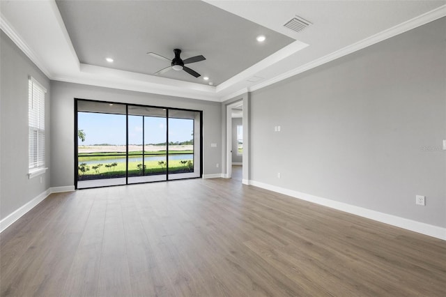 unfurnished room with a raised ceiling, wood-type flooring, ornamental molding, and ceiling fan