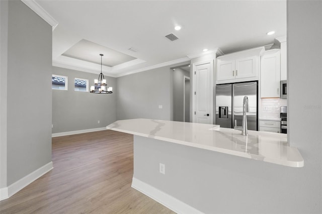 kitchen with kitchen peninsula, white cabinets, stainless steel fridge with ice dispenser, decorative backsplash, and a raised ceiling