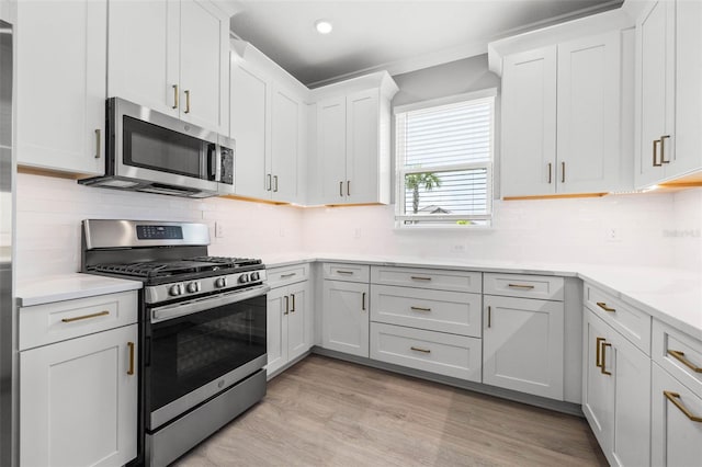 kitchen with white cabinetry, stainless steel appliances, tasteful backsplash, and light wood-type flooring