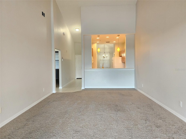 carpeted spare room with a towering ceiling