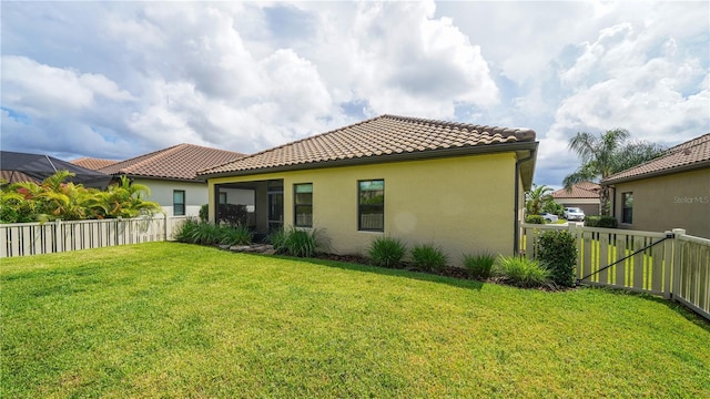 rear view of property with a fenced backyard, stucco siding, a tiled roof, and a lawn