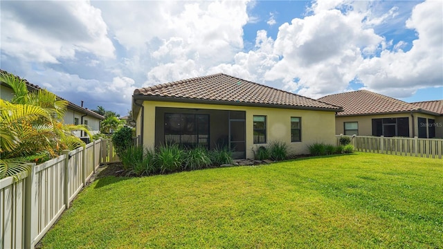 rear view of property with a yard, stucco siding, and a fenced backyard