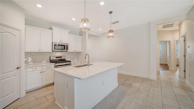 kitchen featuring pendant lighting, sink, white cabinets, a center island with sink, and appliances with stainless steel finishes