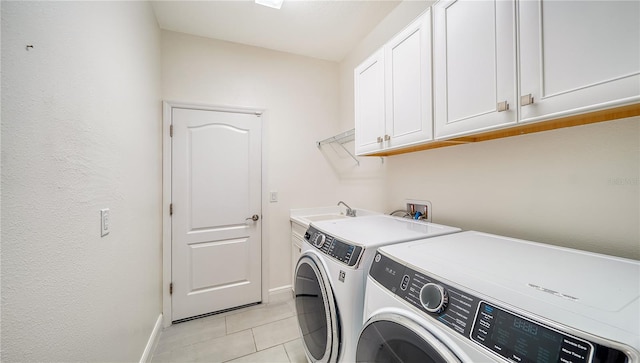 laundry area with independent washer and dryer, cabinet space, a sink, baseboards, and light tile patterned flooring