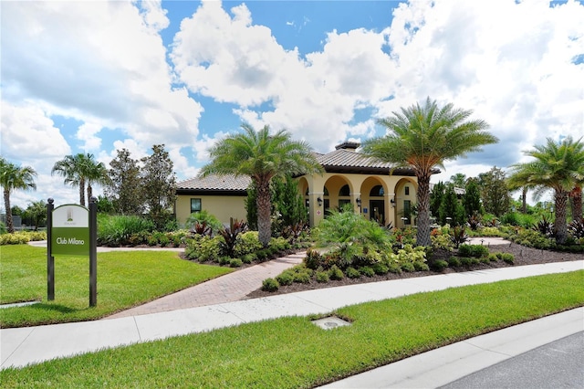mediterranean / spanish home with a front lawn, a tiled roof, and stucco siding