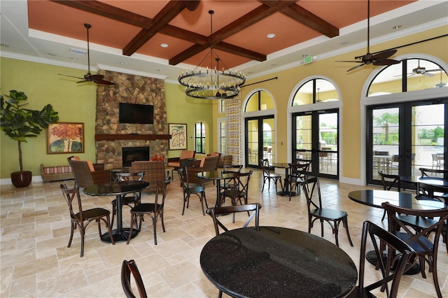 dining room featuring beamed ceiling, coffered ceiling, french doors, and a stone fireplace