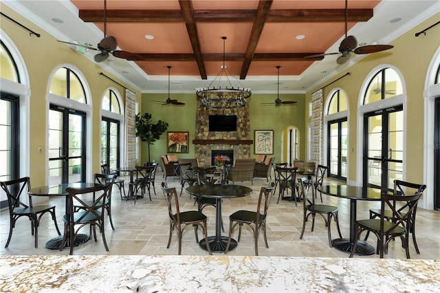 dining area featuring beam ceiling, coffered ceiling, a fireplace, an inviting chandelier, and a towering ceiling