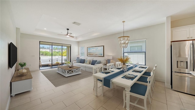 tiled living room featuring ceiling fan with notable chandelier and a raised ceiling