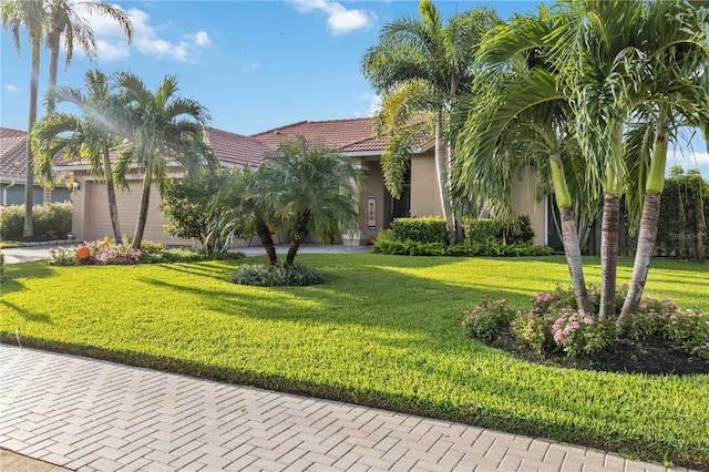 mediterranean / spanish-style home featuring a front lawn and a garage