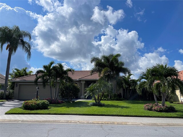 view of property hidden behind natural elements featuring a garage and a front yard