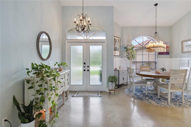 foyer entrance featuring concrete floors, a chandelier, and french doors