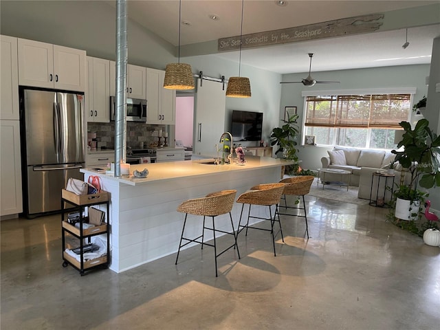 kitchen featuring a breakfast bar, a kitchen island with sink, sink, white cabinets, and appliances with stainless steel finishes