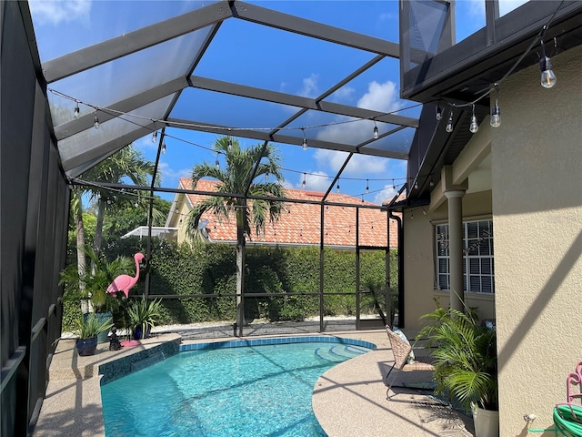 view of pool featuring glass enclosure and a patio