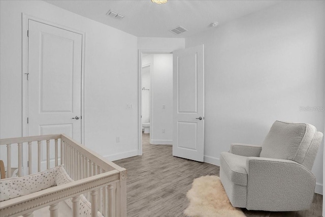 bedroom with light hardwood / wood-style flooring and a nursery area