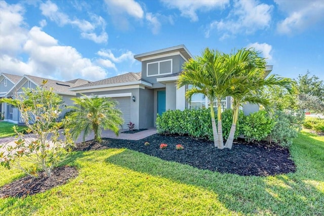 view of front of property with an attached garage, a front lawn, and stucco siding