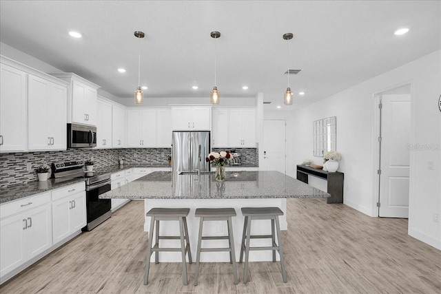 kitchen featuring a center island, white cabinetry, backsplash, and stainless steel appliances