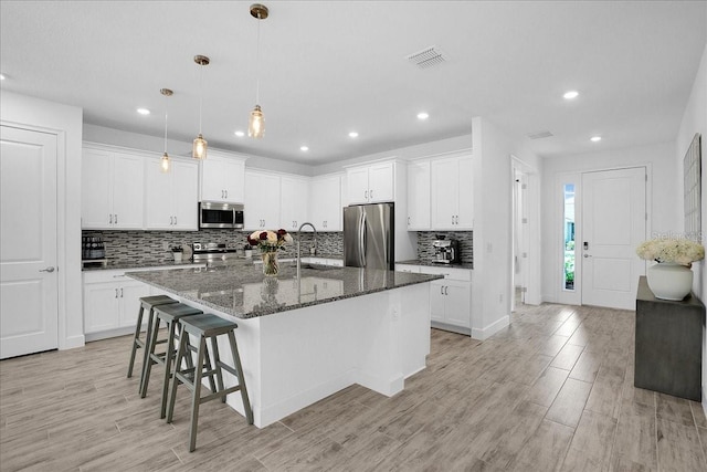 kitchen featuring appliances with stainless steel finishes, decorative backsplash, and light wood-style flooring