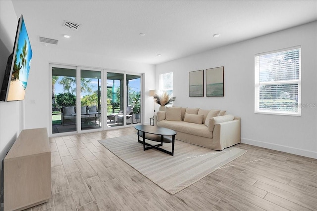 living area featuring visible vents, a healthy amount of sunlight, and light wood-type flooring
