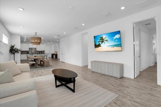 living room featuring recessed lighting, light wood finished floors, and visible vents