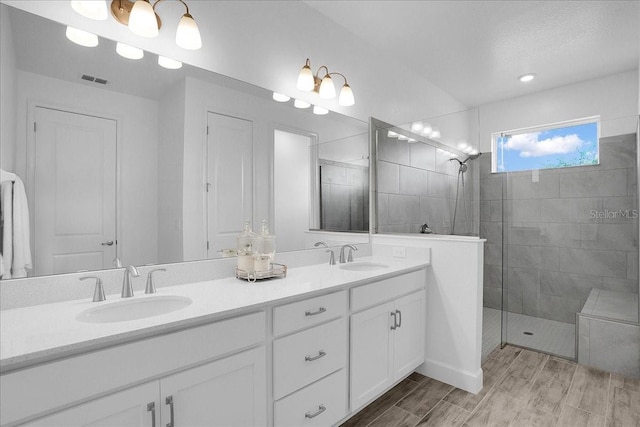bathroom with a sink, a walk in shower, double vanity, and wood finished floors