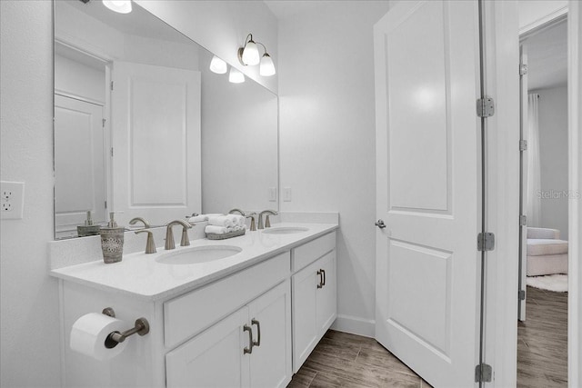 full bath featuring double vanity, baseboards, a sink, and wood finished floors