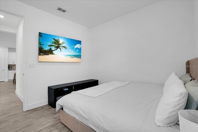 bedroom with visible vents, light wood finished floors, and baseboards