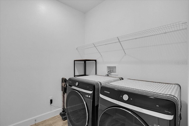 clothes washing area featuring baseboards, laundry area, light wood finished floors, and washer and dryer