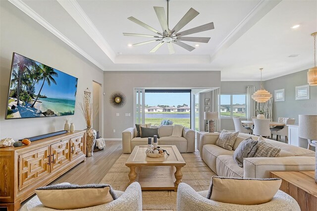 living room with crown molding, a tray ceiling, ceiling fan, and light hardwood / wood-style flooring