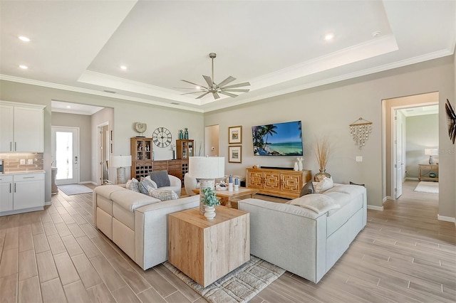 living room featuring ceiling fan, a raised ceiling, and light wood-type flooring