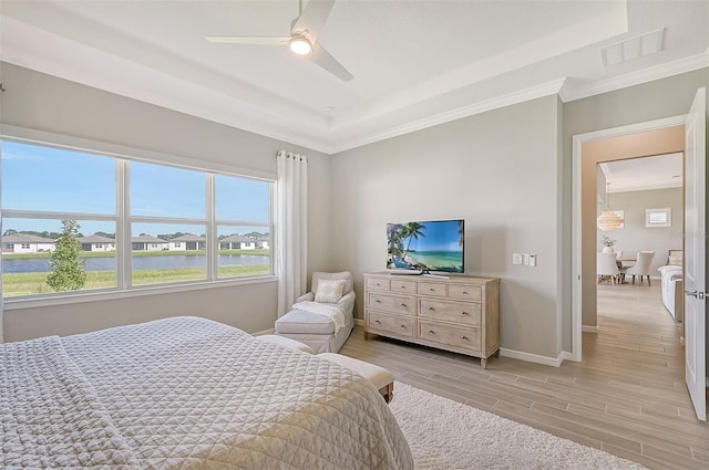 bedroom with ornamental molding, light hardwood / wood-style floors, ceiling fan, and a raised ceiling