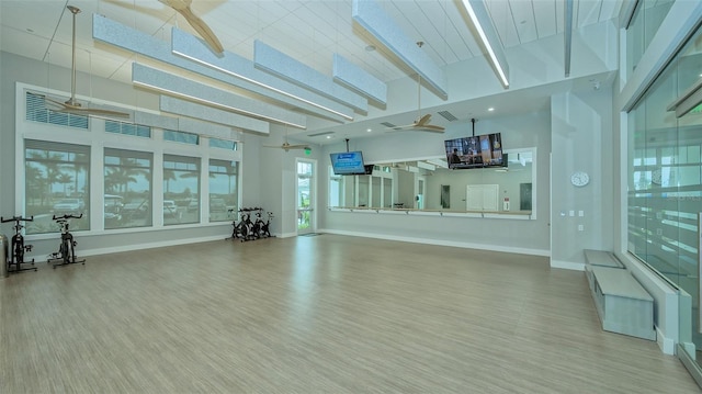 workout room with a high ceiling, ceiling fan, and hardwood / wood-style flooring