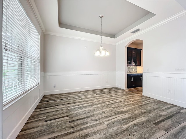 unfurnished dining area featuring a tray ceiling, dark hardwood / wood-style floors, and a notable chandelier