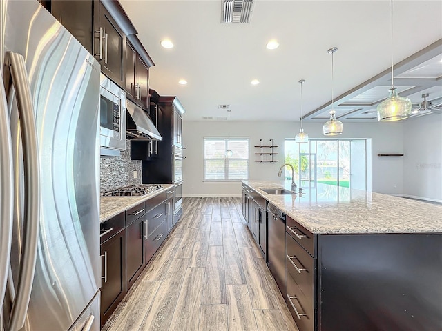 kitchen featuring stainless steel appliances, a spacious island, sink, pendant lighting, and light hardwood / wood-style floors