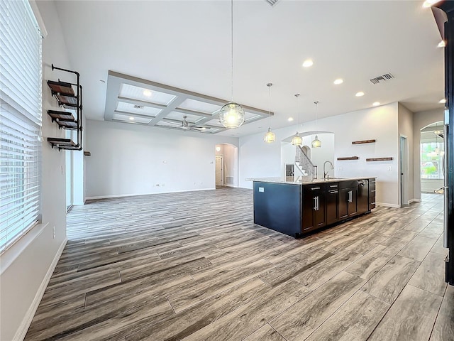 kitchen featuring a kitchen island with sink, coffered ceiling, sink, ceiling fan, and decorative light fixtures