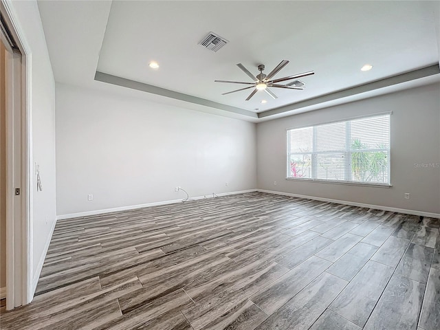 unfurnished room featuring a raised ceiling and ceiling fan