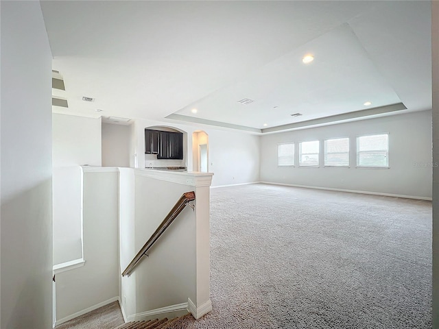 carpeted empty room with a tray ceiling