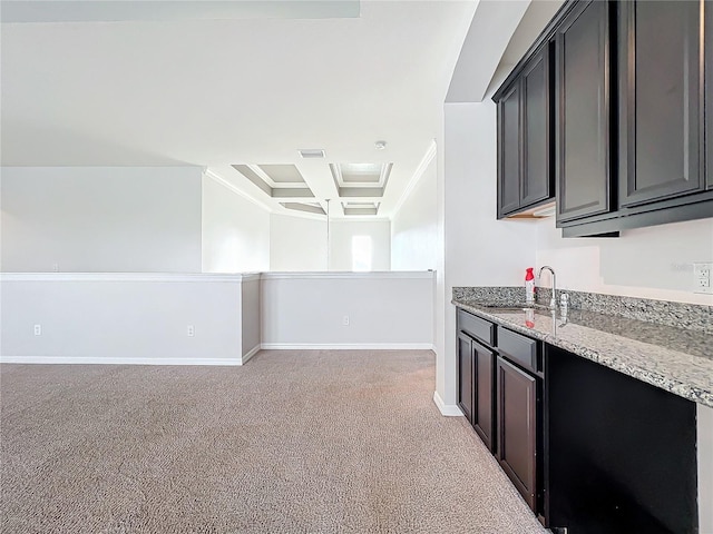 kitchen with light colored carpet, light stone counters, coffered ceiling, and sink