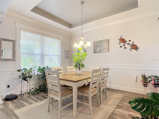 dining space featuring a raised ceiling, a notable chandelier, and hardwood / wood-style flooring