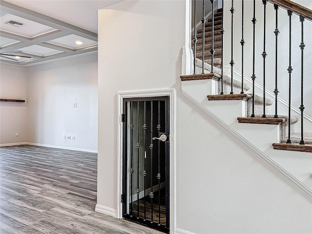 stairs featuring beam ceiling, coffered ceiling, and wood-type flooring