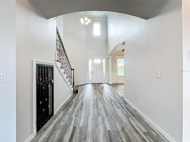 foyer entrance featuring hardwood / wood-style floors, a high ceiling, and a chandelier