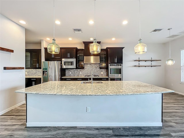 kitchen featuring backsplash, a large island, decorative light fixtures, and appliances with stainless steel finishes