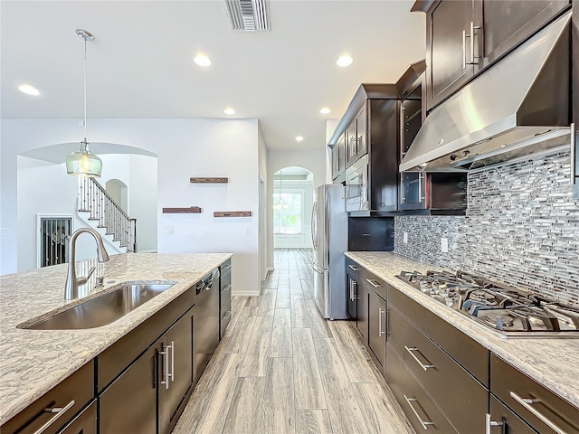 kitchen featuring sink, hanging light fixtures, decorative backsplash, light stone countertops, and stainless steel appliances