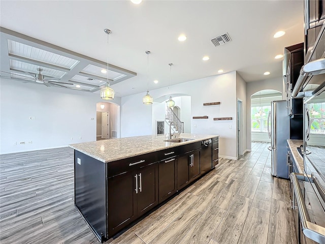 kitchen with ceiling fan, sink, beam ceiling, decorative light fixtures, and an island with sink