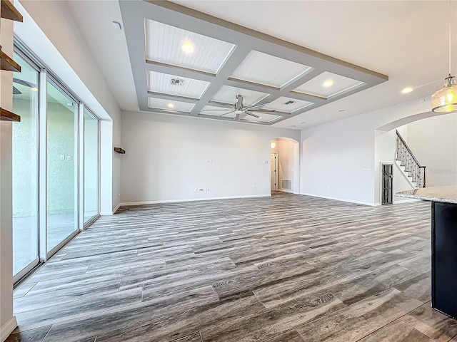 unfurnished living room featuring beam ceiling, plenty of natural light, ceiling fan, and coffered ceiling