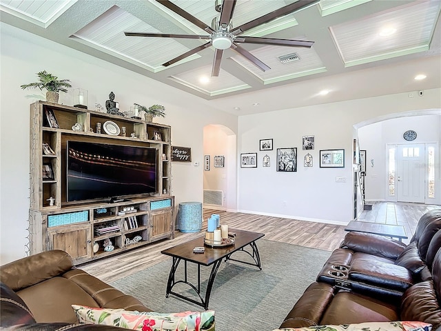 living room featuring ceiling fan, light hardwood / wood-style flooring, beamed ceiling, and coffered ceiling