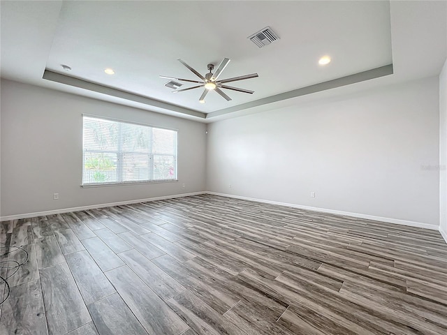 empty room featuring a raised ceiling and ceiling fan