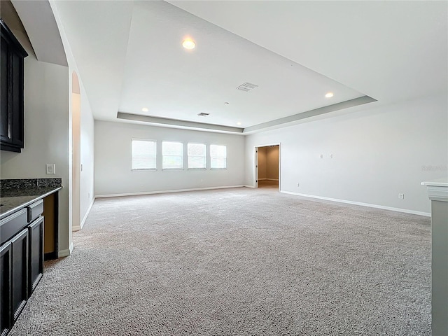 unfurnished living room with a raised ceiling and light colored carpet