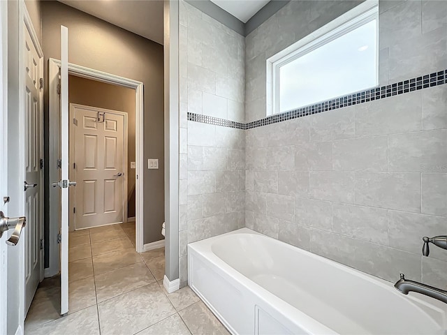 bathroom with tile patterned floors, tiled shower / bath combo, and toilet